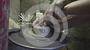 Potter shapes the clay product with pottery tools on the potter`s wheel, craft factory authentic