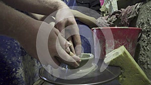 Potter shapes the clay product with pottery tools on the potter`s wheel, craft factory authentic