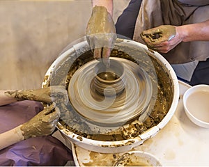 Potter with student mold a pot from clay on a Potter`s wheel