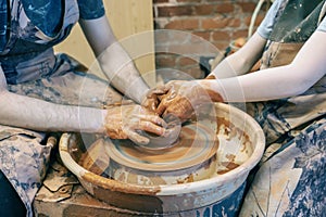 potter teaches the child. A craftsman sits on a bench with a potter& x27;s wheel and makes a clay pot. National craft