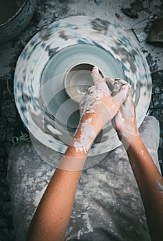 Potter wheel and child hands making a bowl. Top view vertical i