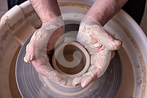 Potter wheel and hands of craftsman making a jug