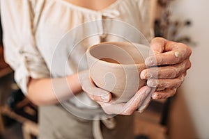 Potter woman keeping clay bowl in dirty palms