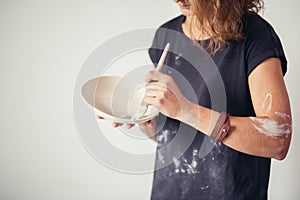 Potter woman paints ceramic cup. Woman working In her pottery studio