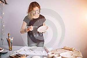 Potter woman paints ceramic cup. Woman working In her pottery studio