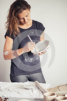 Potter woman paints ceramic cup. Woman working In her pottery studio