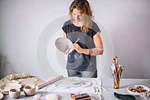 Potter woman paints ceramic cup. Woman working In her pottery studio