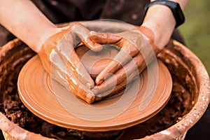 Potter work with clay. Hands of man in shape of heart in clay on pottery wheel mold vase.