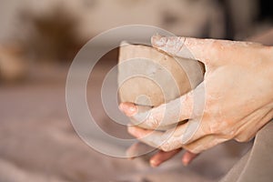 Potter at work. Potter& x27;s hands in clay form a pot in a circle. close-up of female sculpting bowls from raw wet clay.