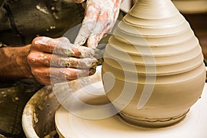 Potter working on potter`s wheel with raw clay with hands, making new bowl