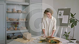 Potter workmanship, ceramist master woman rolls clay with rolling pin on table for making ceramic crockery