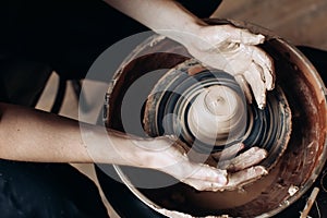 A potter works on a potter`s wheel in his workshop