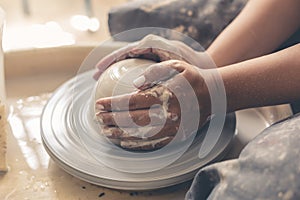 Potter works with white clay on pottery wheel