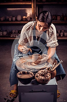 The potter works in the workshop. Hands and a potter& x27;s wheel close-up.