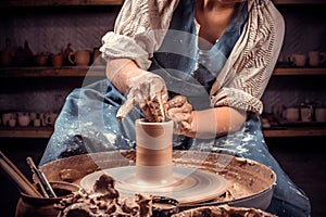 Hands of the master potter and vase of clay on the potter& x27;s wheel close-up. Master crock. Twisted potter& x27;s wheel. photo