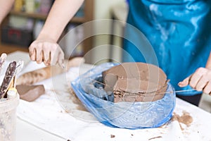 Pottering Concept. Closeup of Hands of Professional Female Ceramist During a Process of Clay Preparation With Wire on Table in