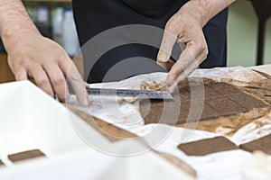 Pottering Concepts. Closeup of Hands of Male Worker Measuring A plate of Wet Clay on Table Before Moulding