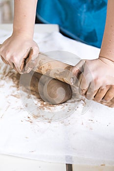 Pottering Ideas and Concepts. Closeup of Hands of Female Worker Rolling a Piece of Wet Clay on Table Before Moulding