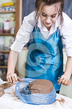 Pottering Ideas and Concepts. Smiling Female Professional Worker Preparing a Piece of Clay Using Special Wire in Professional