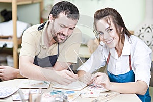 Pottering Ideas. Two Happy Caucasian Ceramists Painting and Glazing