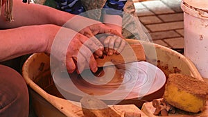 Potters hands guiding child on the ceramic wheel