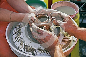 Potters' hands guiding woman's hands
