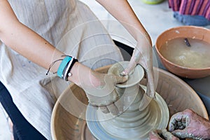 Potters working to shape the clay on the spinning wheel in the workshop. Tanned hands