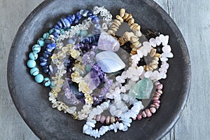 A pottery bowl with healing gem stones and crystals  on a wooden background