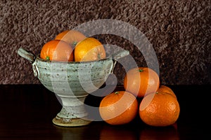 Pottery Chalice Bowl with Satsuma Oranges on a Polished Wooden Table Top