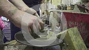 Pottery class and workshop: professional male potter showing how to make clay mug in pottery studio.