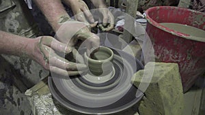 Pottery class and workshop: professional male potter showing how to make clay mug in pottery studio.