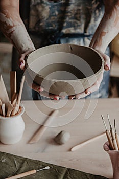 Pottery, clay, ceramics art concept - closeup on hands of young master with the large plate from fireclay photo