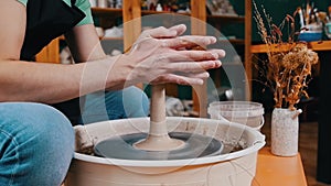 Pottery craftsmanship - a man forming piece of clay in longer shape spinning on a potter`s wheel