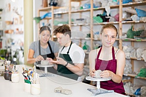 Pottery lesson - teenagers girl and guy intently create dishes from clay