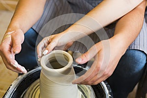 Pottery making. Smeared in clay hands of man and woman on potter`s wheel