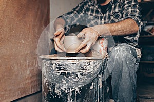 Pottery master works on pottery wheel in workshop
