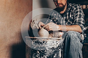 Pottery master works on pottery wheel in workshop