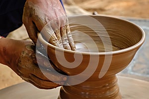 Pottery - skilled wet hands of potter shaping the clay on potter wheel