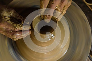 Pottery wheel with potter`s hands .