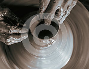 Pottery wheel with potter`s hands .