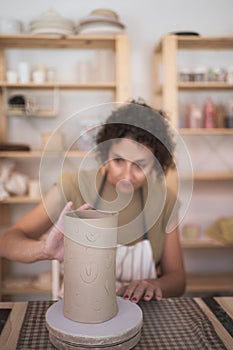 Pottery woman making a handmade ceramic piece at her workshop.