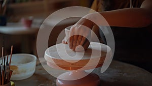 Pottery workshop worker shaping potter bowl in ceramics studio working with raw wet clay on wheel