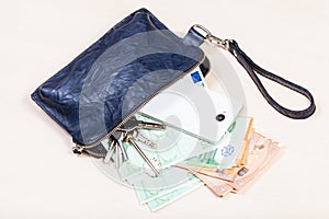 Pouch with phone, keys and many euros on table