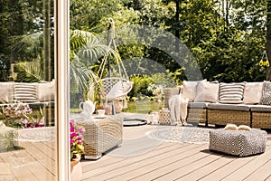 Pouf and rattan sofa on wooden patio with hanging chair in the g