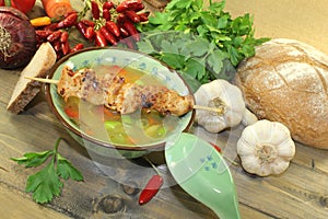Poultry consomme with chicken skewer and greens