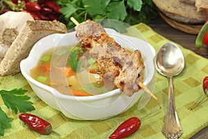 Poultry consomme with chicken skewers and parsley