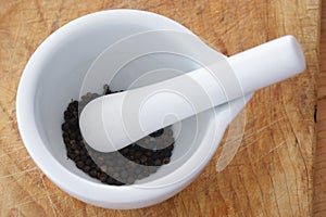 Pounding black pepper in a white bowl