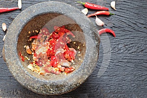 Pounding fresh chili and garlic in stone mortar