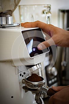 Pour in the beans and hit a button. Barista grind coffee using coffee machine. Fresh ground coffee in portafilter
