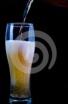 Pour beer into a glass on a black background